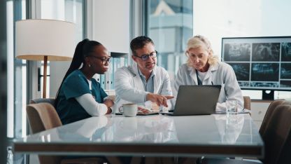 Zwei weibliche und ein Männlicher Arzt sitzen zusammen an einem Tisch und Nutzen das PVS LifeTime Cloud