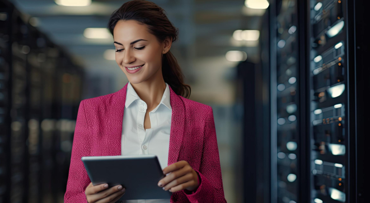 A businesswoman in a data center holding a tablet and smiling while reviewing data.