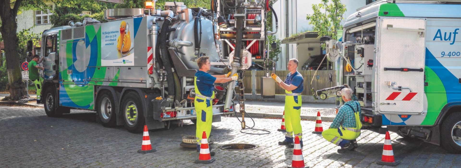 Ein Team der Berliner Wasserbetriebe kümmert sich um einen Kanal auf einer Straße.