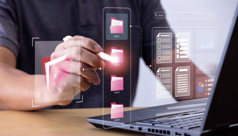 Dateiverwaltung wird imaginär mit Ordner Symbolisiert. Laptop und Hände sind zu sehen.