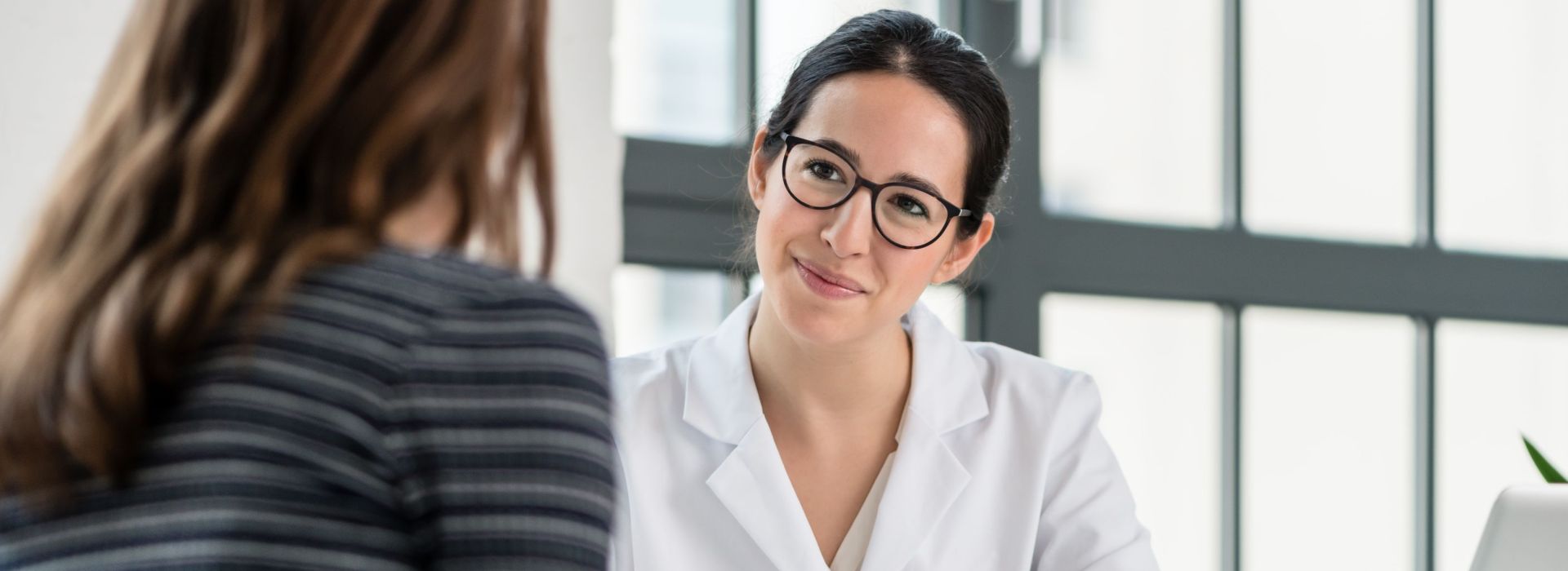 Eine junge Ärztin führt ein Beratungsgespräch mit einer Patientin