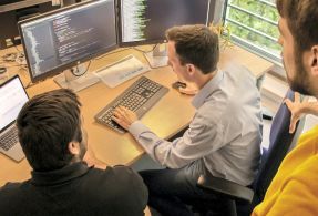 Öffentliche Verwaltung mit AKQUINET - Zukunftsfähige Lösungen für Ihren Bedarf. Für die Digitalisierung der öffentlichen Verwaltung untersuchen drei Mitarbeiter von AKQUINET den Quellcode einer Software.