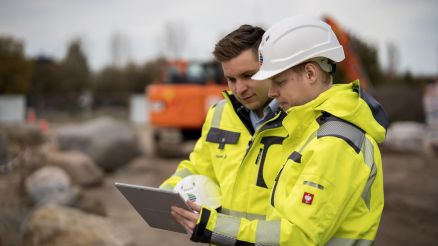 Zwei Mitarbeiter des Rechenzentrum Teams stehen an einer Baugrube und prüfen Daten auf einem Tablet.