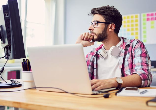 Ein junger Mann sitzt an einem Computer und arbeitet.