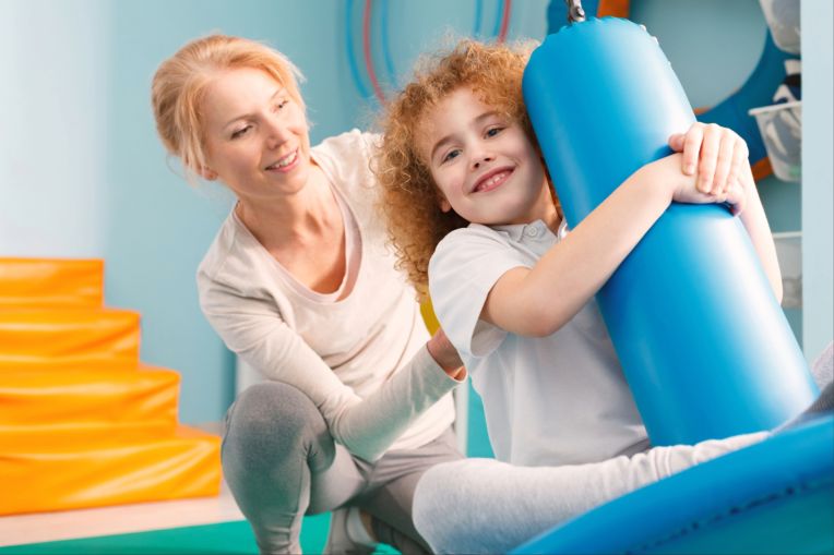 Eine Ergotherapeutin hilft einem jungen Mädchen