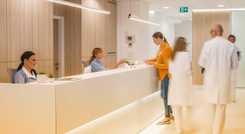 Empfangsbereich einer Praxis mit medizinischem Personal, Patientin und Ärzten