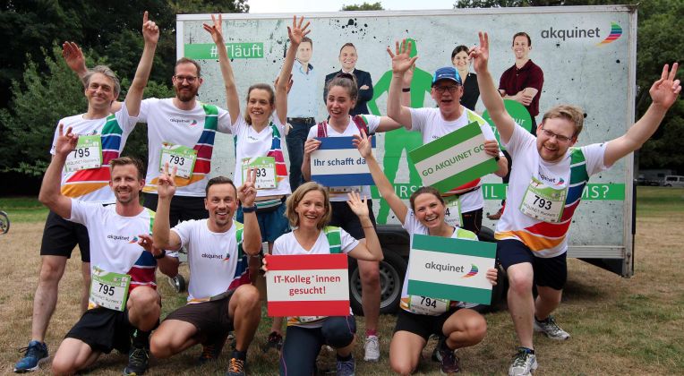 Jubelnde Menschen mit Laufshirts vor einem Anhänger