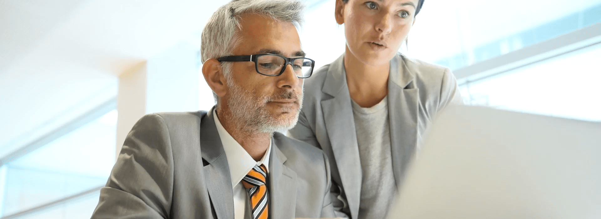 Konzentriertes Team blickt auf Bürotisch mit Laptop