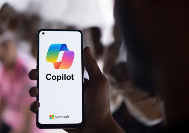 Eine Hand hält ein Smartphone mit dem Microsoft Copilot Logo. Microsoft Fabric sorgt dafür, dass Ihre Unternehmensdaten jederzeit zugänglich und aktuell sind, sodass Copilot speziell auf Ihr Unternehmen zugeschnittene Analysen und Berichte erstellen kann.