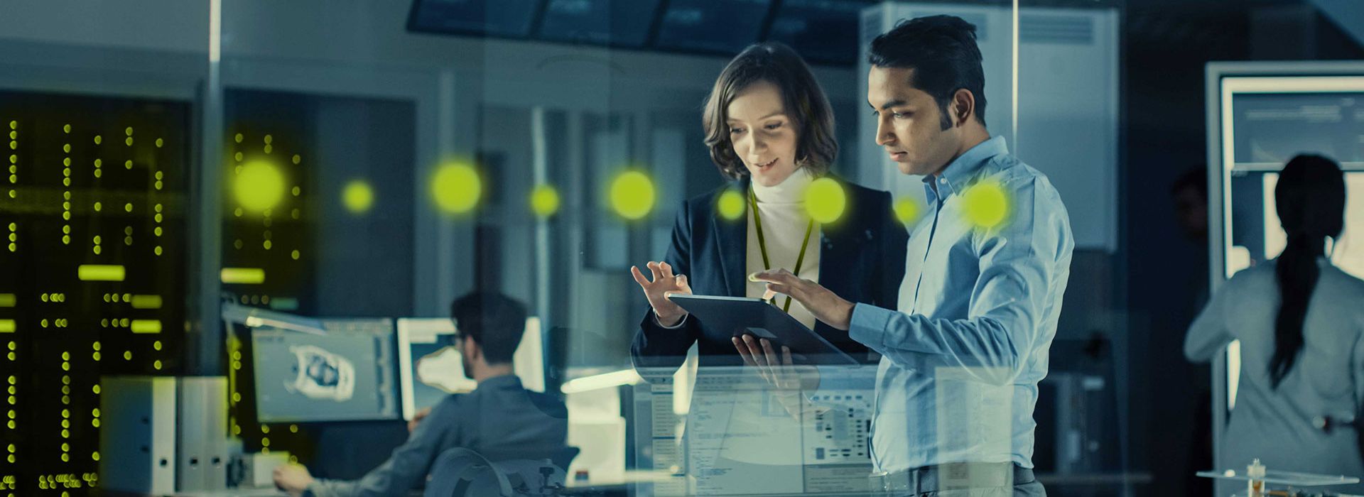 A woman and a man working together on a tablet computer while standing