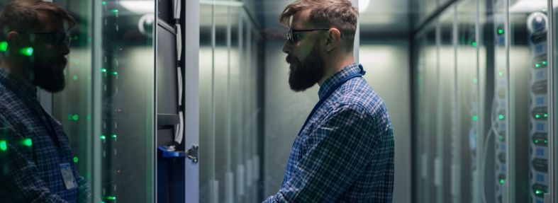 A man stands at a rack and enters data on a keyboard.