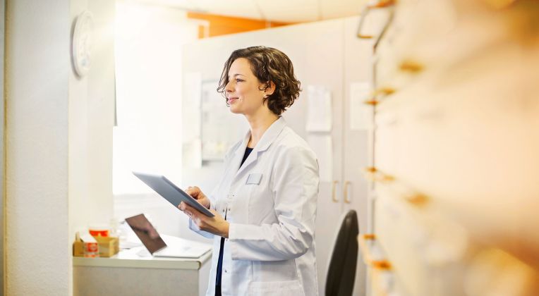 A woman in a coat holds a tray in her hand.