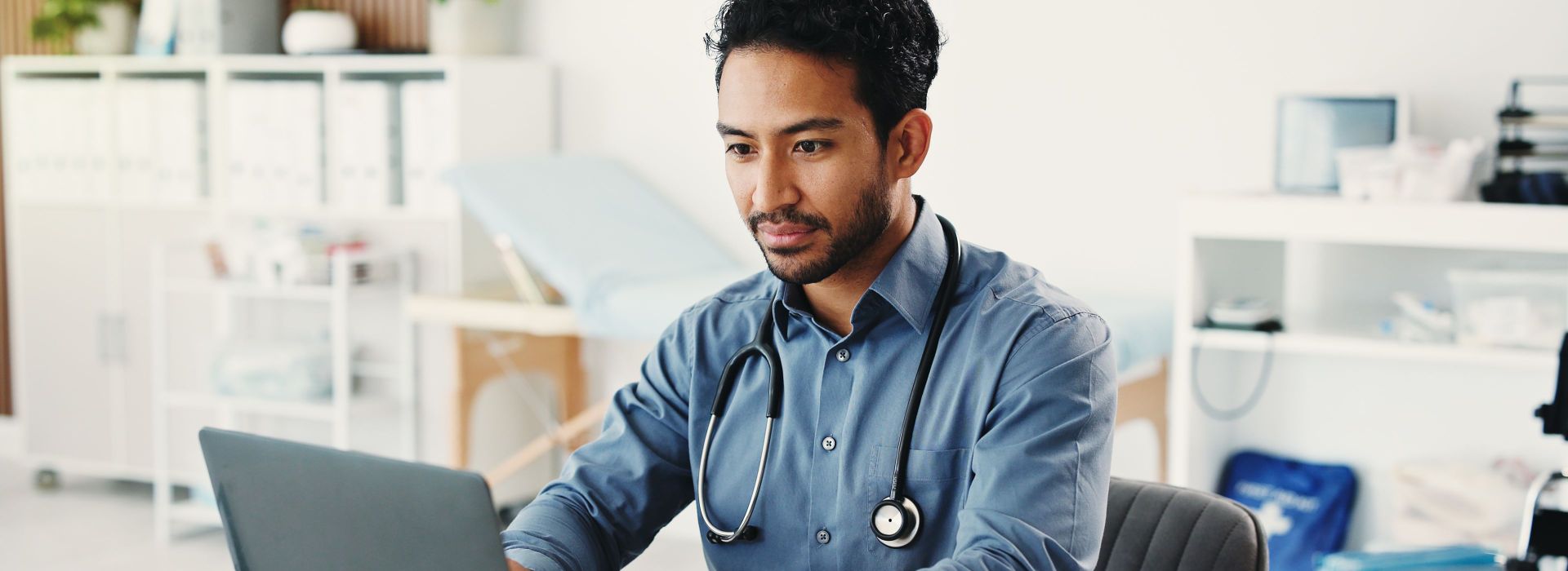 Ein Arzt sitzt an einem Laptop in seiner Praxis und nutzt den browsergestützten KIM-Mailer von AKQUNET um KIM-Nachrichten zu verschicken