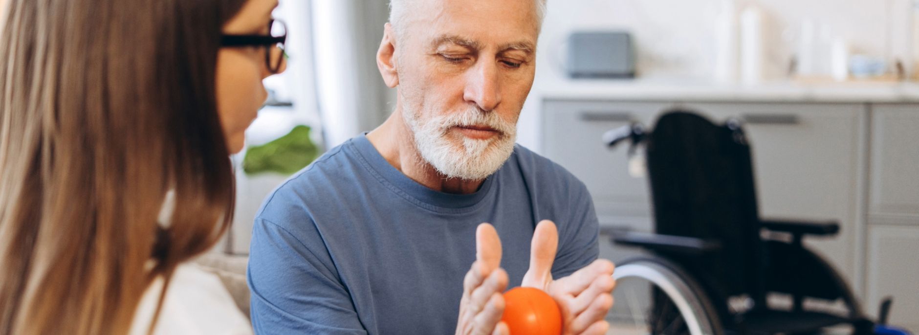 Ein älterer Mann hat eine Ergotherapie-Stunde in der er mit einem kleinen Ball trainiert