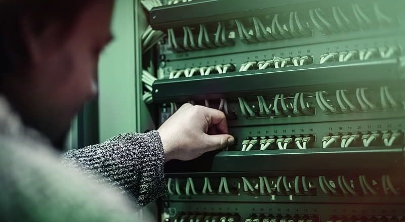 A man is working on a server cabinet.