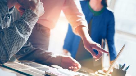 Vor einem Laptop diskutieren drei Personen ihre Projekte.