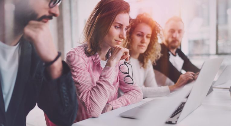 Zwei Frauen und zwei Männer sitzen nachdenklich und konzentriert vor einem Computer.