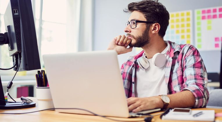 Ein junger Mann sitzt an einem Computer und arbeitet.