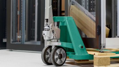 A server cabinet stands on a pallet and is transported with a hand pallet truck.