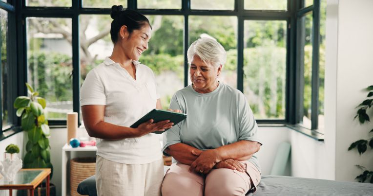 Eine junge Orthopädin zeigt ihrer älterin Patientin die neuste TI Anwendung von AKQUINET auf ihrem Tablet