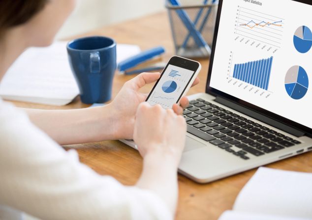 Eine Frau vergleicht Statistiken zwischen Handy und Tablet.