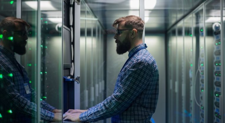 Wir setzen auf höchste Sicherheit und Nachhaltigkeit - Rechenzentren von AKQUINET. Ein Mann steht an einem Rack und gibt Daten auf einer Tastatur ein.