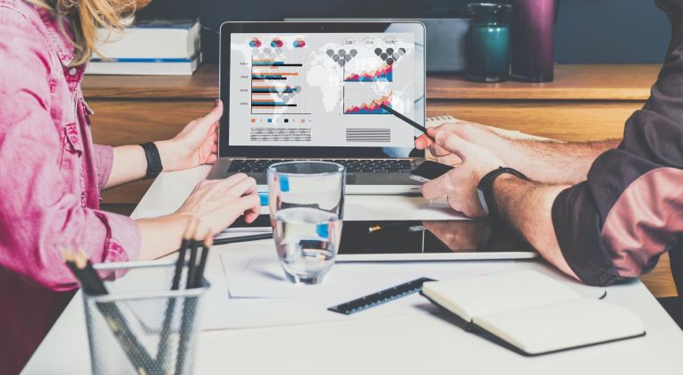 Two people look at a screen with different graphics.