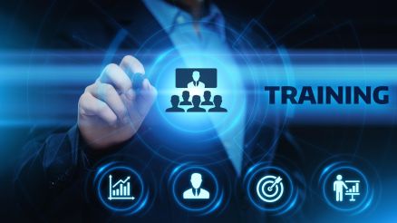 Geschäftsperson tippt auf ein digitales Interface mit Symbolen für Wachstum, Zielerreichung, Personal und Präsentation; in der Mitte das Wort „TRAINING“.