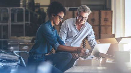 Eine Frau und ein Mann  packen Pakete in einem Lager.