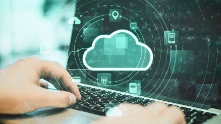 Eine Person arbeitet an einen Laptop und darauf platziert sieht man eine Grafik mit Cloud Symbol mit einem verknüpften Netzwerk.
