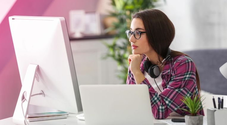 Eine junge Frau schaut konzentriert auf einen Bildschirm und arbeitet.