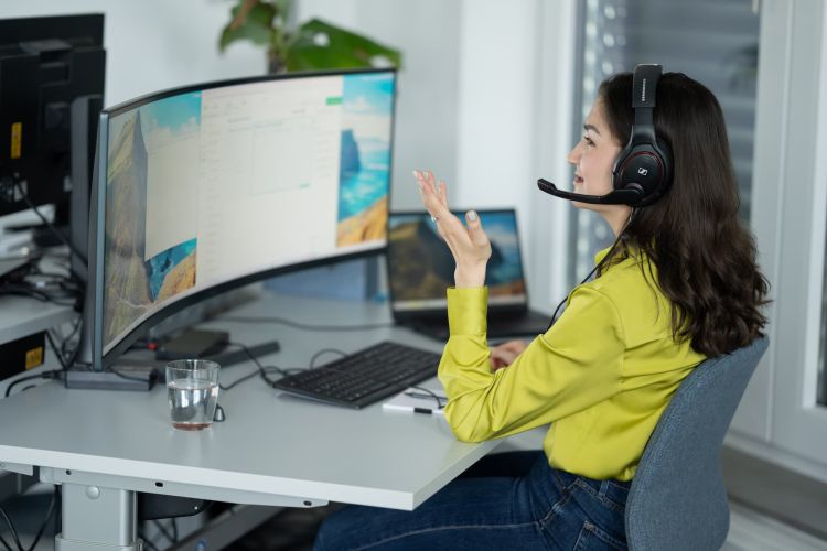 Frau vor dem Bildschirm mit Headset auf.