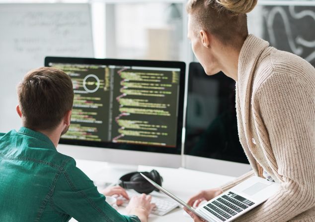 Eine Frau und ein Mann schauen sich Informationen auf einem Monitor an.