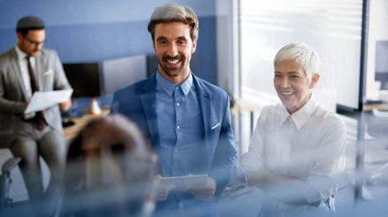 Kunde wird von zwei Microsoft Expert*innen zur Digitalisierung in seinem Vertrieb beraten. Ein Mann überprüft die Costumer Journey im Hintergrund.