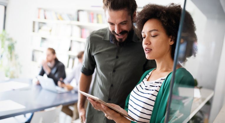 A man and a woman look at information on a tablet.