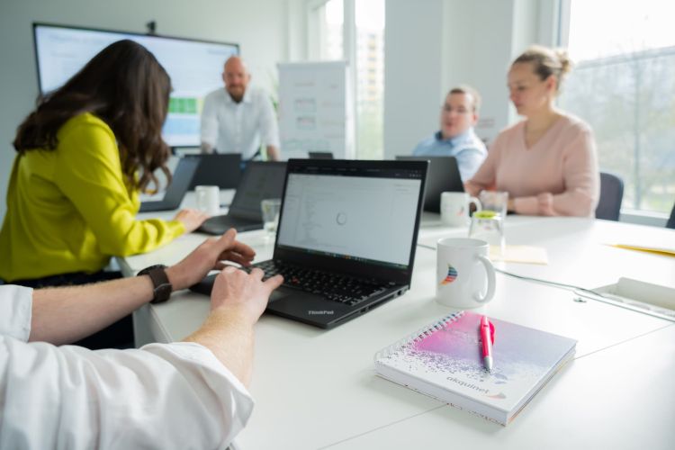 Schulungsteilnehmer sitzen mit Laptop am Tisch.