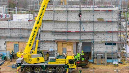 Ein gelber Kran hebt den Transformator auf die Baustelle des Rechenzentrum Victoria Park Hamburg