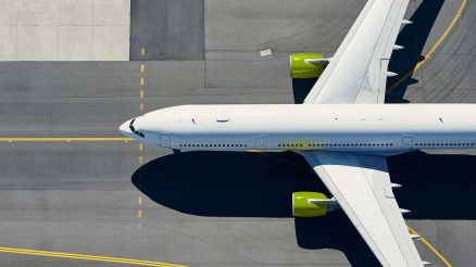 Ein Flugzeug steht auf dem Rollfeld eines Flughafens. Blick von oben.