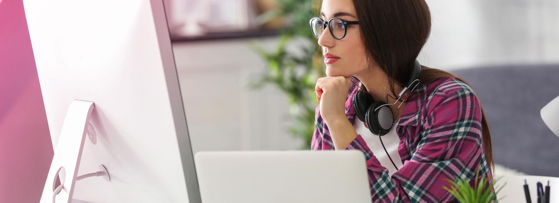 Eine junge Frau schaut konzentriert auf einen Bildschirm und arbeitet.