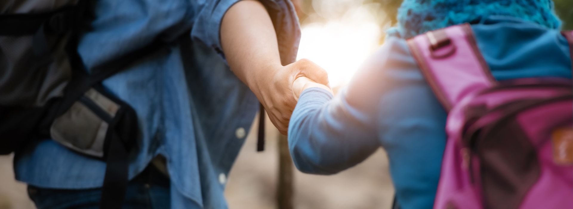 Two people help each other on a hike and hold hands supportively.