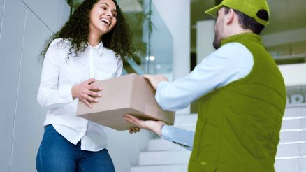 Ein Paketbote übergibt einer Frau ein Paket.