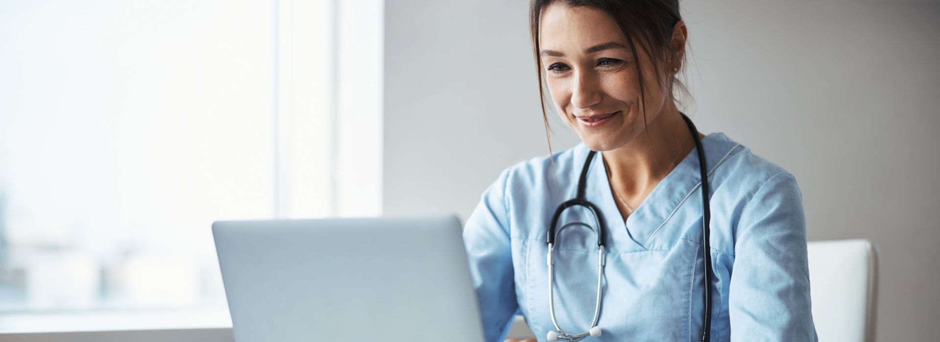 Eine Ärztin sitzt an einem Laptop und verschickt über den KIM-Mailer von AKQUINET eine KIM-Nachricht