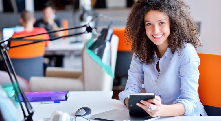 Ein junges Team sitzt vor einem Rechner zusammen auf der Couch und arbeitet.