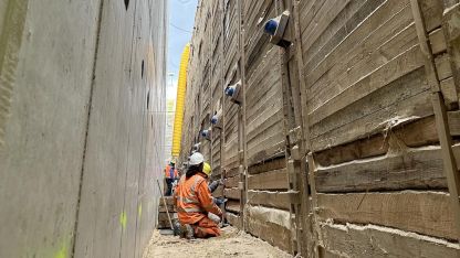 Ein Bauarbeiter sitzt in der Baugrube zur Befüllung von Außenwand und Verbauwand.