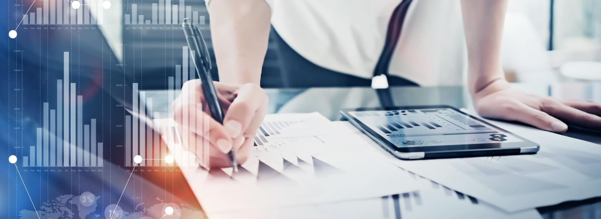 Frau lächelt in die Kamera mit einem Blattpapier in der Hand, vor sich auf dem Tisch