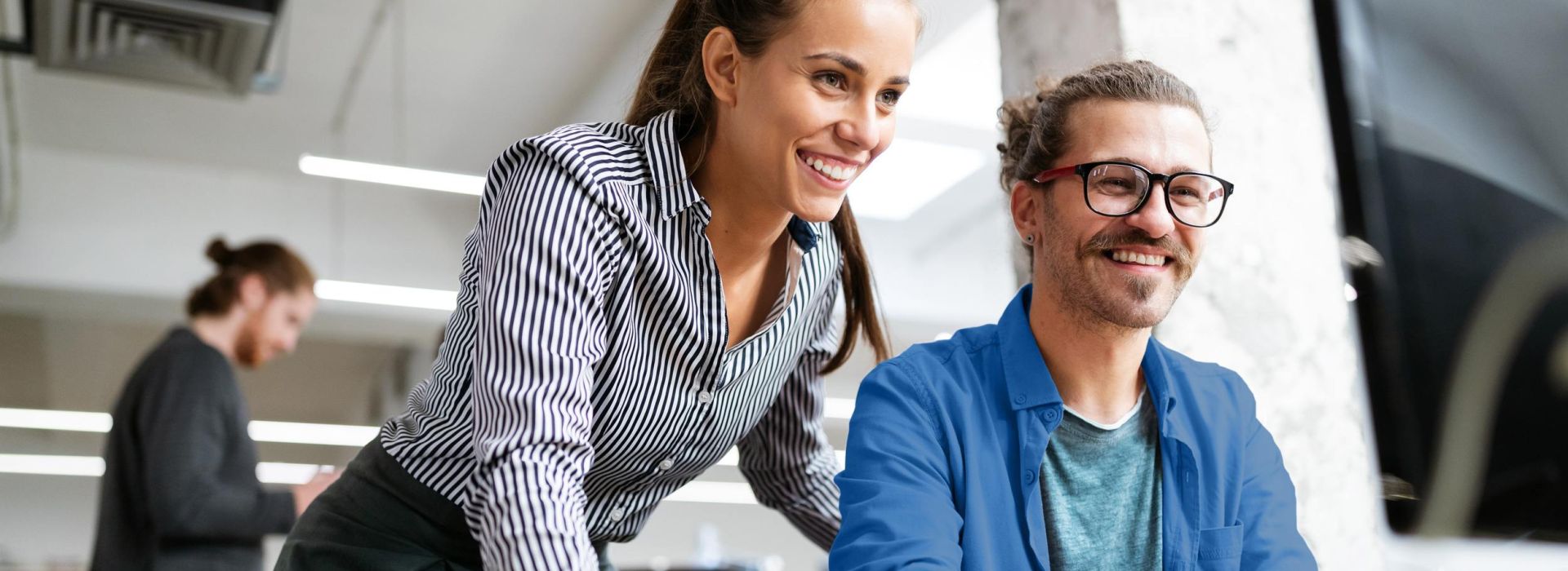 Eine Frau und ein Mann schauen auf einen Monitor.