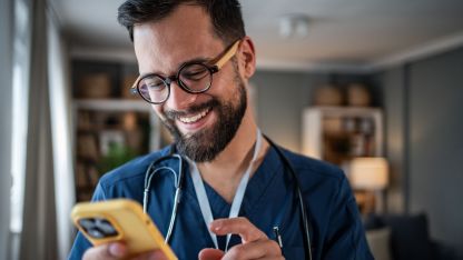 Ein junger Arzt nutzt begeistert den LifeTime Professional Messenger auf seinem Smartphone