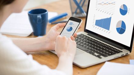 Eine Frau vergleicht Statistiken zwischen Handy und Tablet.