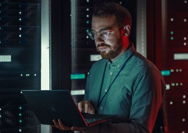 An IT administrator works on a tablet to check data on a server.