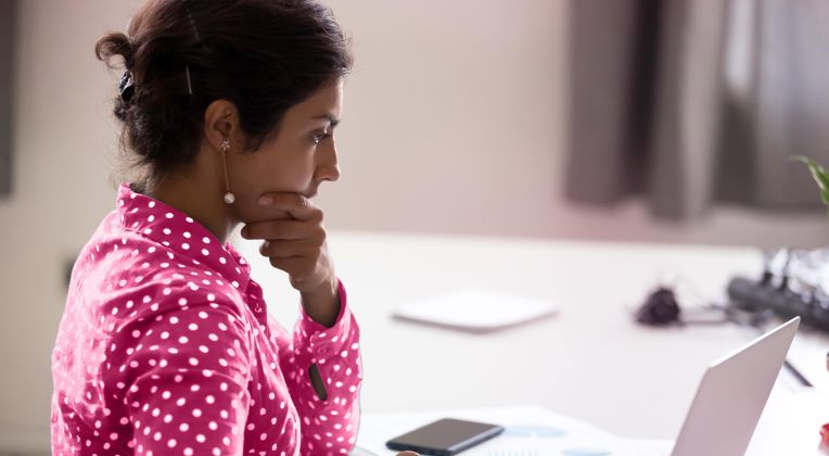 A woman with a pink blouse on the PC can be seen.